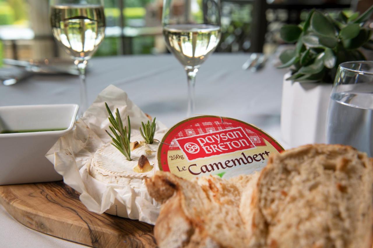Macdonald Bath Spa Hotel Exterior foto The photo features a dining setting that includes a wooden platter with a round Camembert cheese, garnished with fresh rosemary sprigs. Nearby, there is a serving of bread, likely sliced, and a small bowl, potentially for dipping or spreading. In the