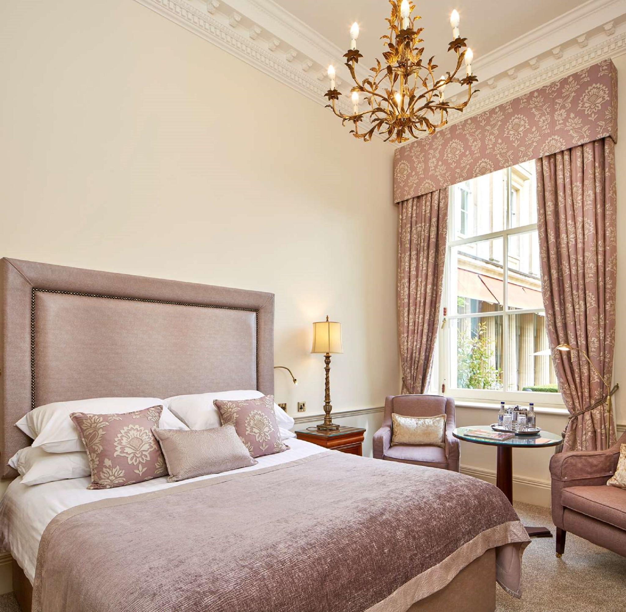 Macdonald Bath Spa Hotel Exterior foto The photo shows a beautifully decorated hotel room. It features a large bed with a plush headboard, adorned with several decorative pillows. The walls are painted in a soft color, and there is a chandelier hanging from the ceiling. Natural light come