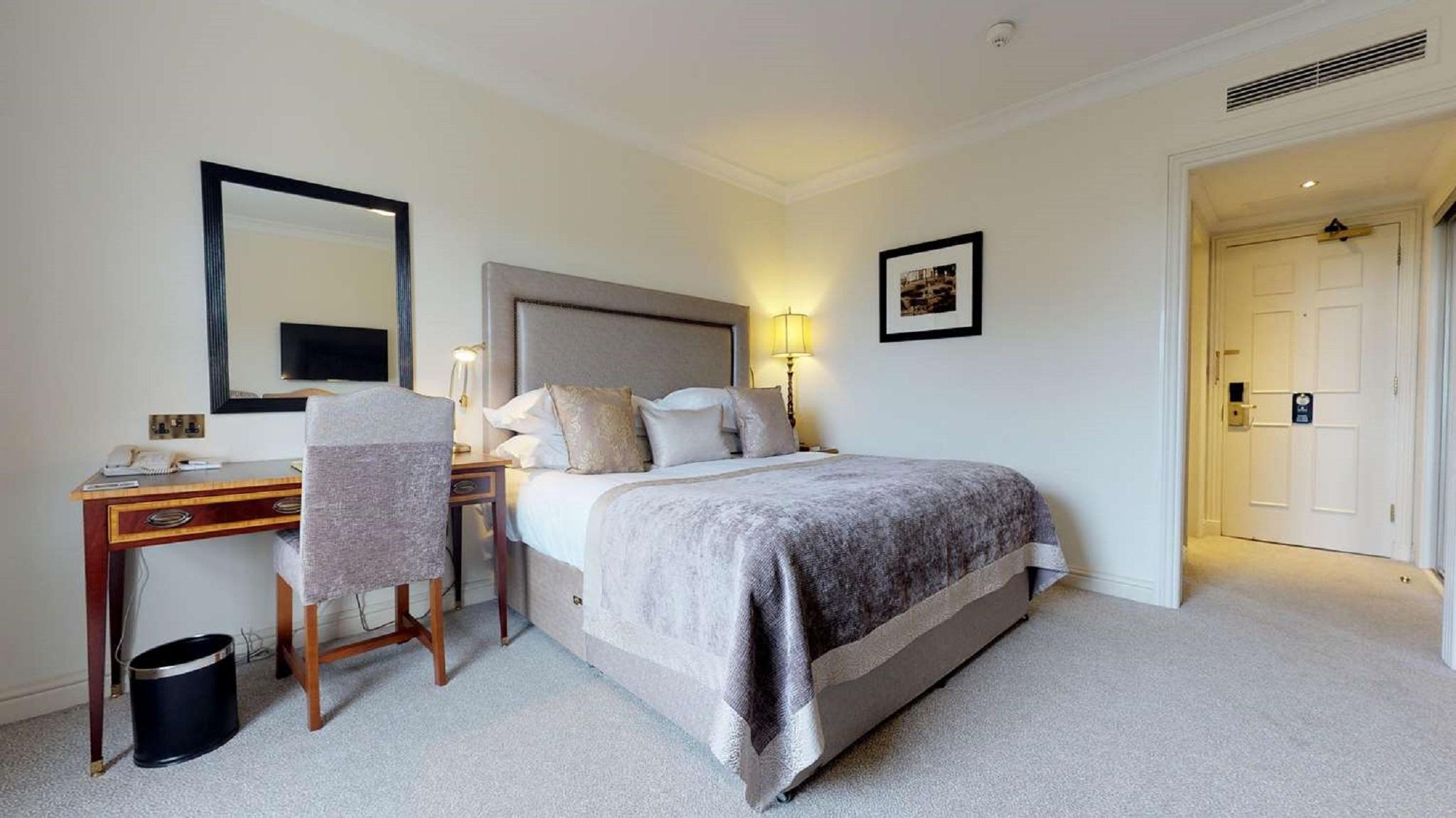 Macdonald Bath Spa Hotel Exterior foto The photo shows a well-decorated hotel room. In the center, there's a comfortable bed with plush bedding and decorative pillows. A bedside table with a lamp is positioned next to the bed. To the left, there's a small desk with a chair, accompanied by