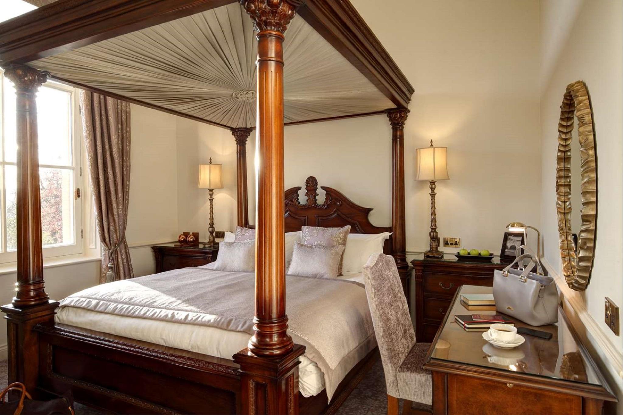 Macdonald Bath Spa Hotel Exterior foto The photo shows a beautifully designed bedroom featuring a four-poster bed with a canopy. The bed is adorned with white linens and decorative pillows. On either side of the bed, there are bedside tables with lamps providing warm lighting. Large windo
